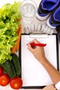 Healthy lifestyle concept. Writing weight loss plan with fresh vegetable diet and fitness
