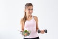 Healthy lifestyle, diet, fitness and people concept - young woman is eating a salad and doing sport with dumbbell on