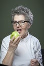 Age, healthy eating, food, diet and people concept - portrait of beautiful old woman biting green apple Royalty Free Stock Photo