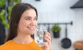 Healthy lifestyle. Female drinking still water standing. Young smiling woman holding glass of clean fresh water Royalty Free Stock Photo