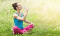 Healthy lifestyle and fitness concept in the park. Beautiful girl is going to drink water from a bottle, sitting in the Royalty Free Stock Photo