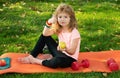 Healthy lifestyle and healthy food concept. Little boy child in sportswear eating apple sitting on sport mat after Royalty Free Stock Photo