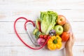 Healthy lifestyle, food and nutrition concept. Close up doctor woman hand holding plate of fresh vegetables and fruits with Royalty Free Stock Photo