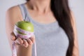 Healthy lifestyle, food and sport concept. Close up young woman hand holding measuring tape around fresh green apple Royalty Free Stock Photo
