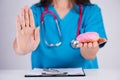 Healthy lifestyle, food and sport concept. Doctor woman hand holding donut or unhealthy food and outstretched hand showing stop Royalty Free Stock Photo