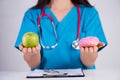 Healthy lifestyle, food and sport concept. Healthy versus unhealthy. Doctor woman hand holding donut and green apple