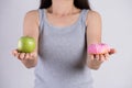 Healthy lifestyle, food and sport concept. Healthy versus unhealthy. Woman hand holding donut and green apple