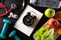 Healthy lifestyle, food and sport concept. Top view of alarm clock on plate with athlete`s equipment Stethoscope measuring tape Royalty Free Stock Photo