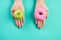 Healthy lifestyle, food and sport concept. Top view of healthy versus unhealthy. Woman hand holding donut and green apple on blue