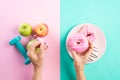 Healthy lifestyle, food and sport concept. Top view of Woman hand holding donut and measuring tape with athlete`s equipment Royalty Free Stock Photo