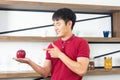 Healthy lifestyle and freshness concept. Smart, young and healthy Asian man eating apple in the loft style kitchen room Royalty Free Stock Photo