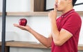 Healthy lifestyle and freshness concept. Smart, young and healthy Asian man eating apple in the loft style kitchen room Royalty Free Stock Photo