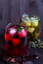 Glass of iced red hibiscus tea and dry flowers on a wooden table. Royalty Free Stock Photo