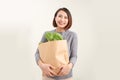 Happy woman holding paper bag full of fresh vegetable groceries isolated on white copy space background Royalty Free Stock Photo