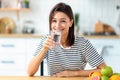 Healthy lifestyle happy smiling young woman sits at home at the kitchen table holding a glass of fresh clean water Royalty Free Stock Photo