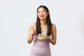 Healthy lifestyle, leisure and people emotions concept. Cheerful smiling asian girl eating salad and laughing happy Royalty Free Stock Photo