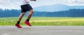 Healthy lifestyle and losing weight. Young man running on concrete road in summer with grassland and forest landscape