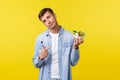Healthy lifestyle, people and food concept. Reluctant handsome young man pointing finger at disgusting salad, unwilling Royalty Free Stock Photo