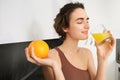 Healthy lifestyle and sport. Beautiful smiling woman, drinking fresh orange juice and holding fruit in her hand Royalty Free Stock Photo