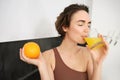 Healthy lifestyle and sport. Beautiful smiling woman, drinking fresh orange juice and holding fruit in her hand Royalty Free Stock Photo