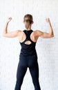 Rear view of an athletic woman in black sportwear showing her back and arms muscles Royalty Free Stock Photo