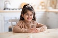 Healthy Liquid. Cute little girl sitting in kitchen holding glass of water Royalty Free Stock Photo