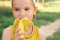 Healthy little boy eating bananaon nature background. Happy kid enjoy eating fresh fruit.