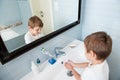 Healthy little caucasian kid washing his hands in blue bathroom indoors Royalty Free Stock Photo