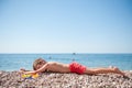 Healthy little kid in red shorts lying on summer beach during vacation tour