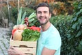 Healthy looking farmer holding a box of veggies