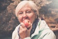 Healthy looking senior woman with grey hair eating apple outside Royalty Free Stock Photo