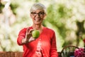 Senior woman with grey hair holding apple outside in the park Royalty Free Stock Photo