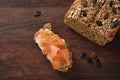 Healthy low carb protein bread from lupine flour and pumpkin seeds with salmon and herb garnish on a dark rustic wooden table,
