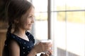 Adorable little girl looking at window holding glass of milk Royalty Free Stock Photo