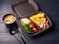 Healthy lunch box with sandwich and fresh vegetables and soup on black wooden background