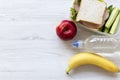 Healthy lunch box with sandwich, fruits and bottle of water on white wooden table, top view. From above, flat, overhead