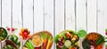 Healthy lunch food bottom border with nutritious buddha bowl, lettuce wraps, sandwiches, salad and vegetables, top view over a whi Royalty Free Stock Photo