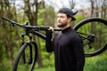 Healthy man bicycler carrying mountain bike while exploring in woods