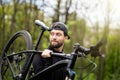 Healthy man bicycler carrying mountain bike while exploring in woods