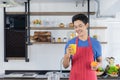 Healthy man with casual clothes is smiling and holding fresh homemade orange juice glass and fresh orange, in kitchen room at home Royalty Free Stock Photo