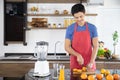 Healthy man is slicing fresh orange fruit to make juicing, orange juice in kitchen room at home