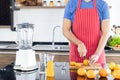 Healthy man is slicing fresh orange fruit to make juicing, orange juice in kitchen room at home