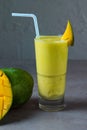 Healthy Mango Juice fresh juice served in glass with mango slice and straw side view on grey background Royalty Free Stock Photo