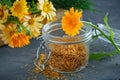 Healthy marigold flowers. Medicinal herbs in wooden crate and glass jar of dry calendula petals