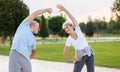 Happy smiling mature man and woman in sportswear stretching body while warming up together outdoors Royalty Free Stock Photo
