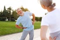 Shot of happy smiling mature family man and woman in sportswear stretching arms while warming up together outdoors in park on sunn Royalty Free Stock Photo