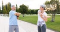 Happy smiling mature man and woman in sportswear doing arm stretching while warming up together outdoors Royalty Free Stock Photo