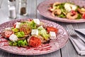 Healthy mixed Greek salad served on a pink plate with silver fork containing crisp leafy greens, microgreen, feta, onion Royalty Free Stock Photo