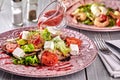 Healthy mixed Greek salad served on a pink plate with silver fork containing crisp leafy greens, microgreen, feta, onion Royalty Free Stock Photo