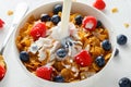 Healthy Morning Breakfast honey Corn flakes with fresh fruits of Raspberry, blueberries and pouring milk in bowl. Royalty Free Stock Photo